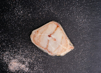Raw Catfish steak with salt on shale board. Top view. 