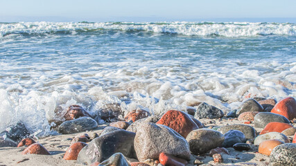 Fototapeta na wymiar sea foam on wet pebbles on the beach on a sunny day, close up