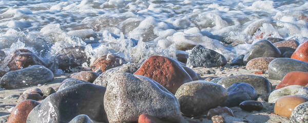 sea foam on wet pebbles on the beach on a sunny day, close up