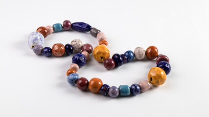 Isolated multi colored natural ceramic beads are on the white background. Traditional old Slavic culture.