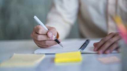 Male hands with pen writing on notebook.