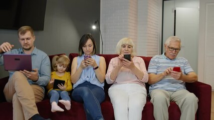 Addicted to gadgets family using mobile phone, tablet, laptop ignoring each other at home. Senior couple, woman, man, child girl involved in chatting in social networks, internet obsession concept - Powered by Adobe