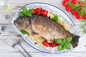 whole baked carp in foil with lemon in the oven, top view, horizontal