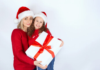 Happy mother and daughter in Christmas hats and red sweatshirts together hold a Christmas gift in a white box tied with a red ribbon. Happy New Year. Isolate on a white background. Copy space. Mock up