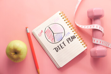 Diet plan with almond nut, dumbbells, apple on table