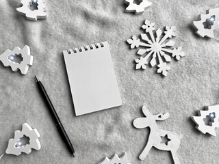 Flat lay winter composition.  Christmas New Year concept.  Blank white spiral notebook in a cozy frame of winter white decor on a soft knitted light background.  Copy space, top view.  Monochrome blac