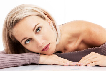 Beautiful young blonde woman lies on the table. Close-up. White background.