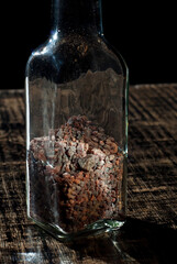 Tibetan black salt in a glass jar close up. Salt on a black, old shabby board. Contrasting dramatic light as an artistic effect. Free space and copy space for text near condiments.