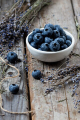 Juicy blueberries with sprigs of lavender on a wooden background.