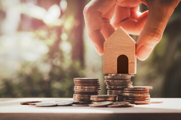 Hand holding house model put on stack coins, Savings for buy house , property, mortgage and real estate investment.Property real estate and financial concept.