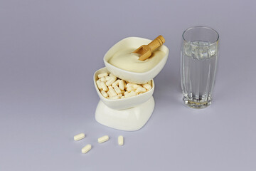 Collagen protein powder and capsules in jars, a glass of water. Natural beauty and health supplement for skin, bones, joints.