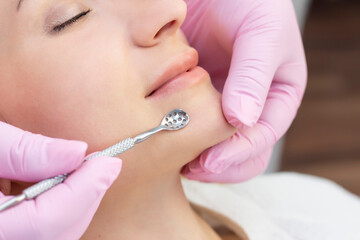 Procedure for cleaning the skin of the face with a steel appliance with a spoon from blackheads and acne.