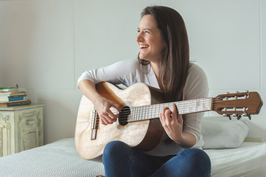 Image of happy beautiful woman playing guitar