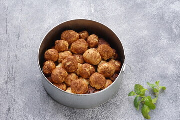 Grainy texture of Monkey bread or Cinnamon pull apart bread in a circle cake mold. Isolated grainy texture gray background with a Mint leaf