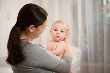 Close up portrait of beautiful young mother girl kissing her newborn baby