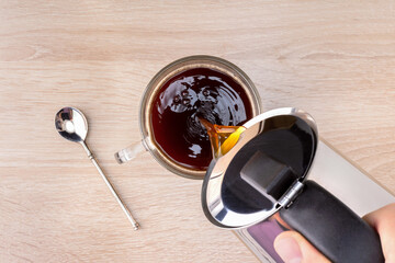 Man pouring coffee in cup on wooden table. Top view with copy space.