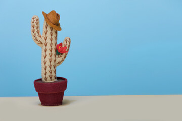 Potted felt toy Cowboy cactus with hat is on blue background. Concept father's day. Copy space.