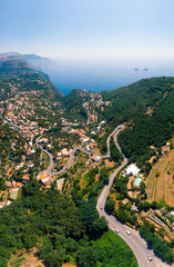 Aerial daytime view of Sorrento coast, Italy. Streets of city with hotels and restaurants are located on rocky seashore, mountains and sea. Danger curve roads. Vertical photo