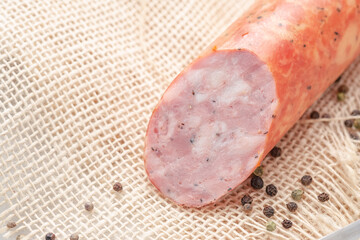 Large smoked salami sausage cut in half on rustic background, copy space
