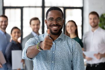 Best ever. Portrait of loyal excited black male client customer demonstrating thumb up sign recommending good product service, happy african employee looking at camera glad to work in company staff