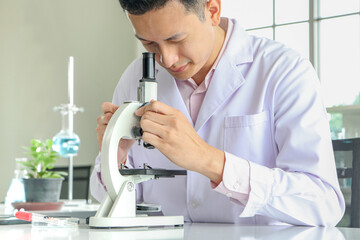 Asian scientists or chemists use a microscope.