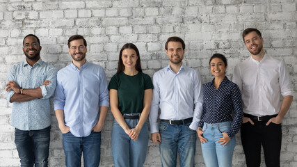 Happy people. Group portrait of young successful diverse businesspeople standing in row looking at...