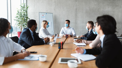 People In Face Masks Sitting During Corporate Meeting In Office