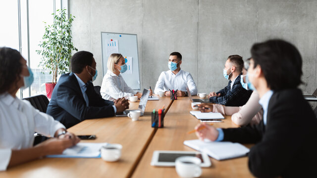 People In Face Masks Sitting During Corporate Meeting In Office