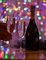 girl holding a bengali fire and a glass of champagne on a beautiful festive bokeh background, consisting of colored out of focus lights on a dark background