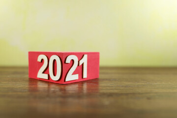 Letters on the year 2021 attached to red color block reflected on the wooden table 