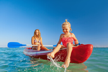 Happy family - young mother, children have fun on boat walk. Woman and child paddling on kayak....