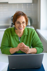 Portrait of a senior woman with headset having online conversation.