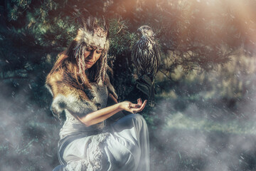 beautiful shamanic woman with falcon in the nature.