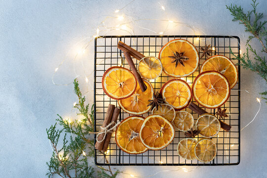 dried oranges, lemons, cinnamon sticks and anise stars on a background of Christmas lights and fir branches. ingredients for cooking or christmas decoration. flat lay. space for text