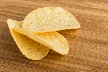 Potato chips on a wooden board. Salty snacks. Close-up