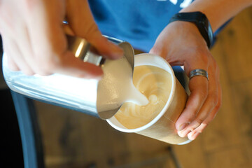 Barista prepares coffee in a paper cup