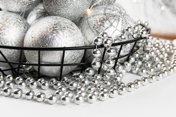 Christmas composition. Christmas balls and silver beads in an iron basket on a white background.