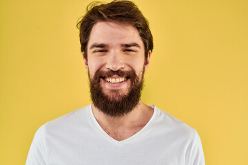 A man in a white t-shirt gestures with his hands lifestyle cropped view yellow background more fun