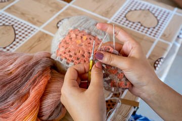 Female hands knitting with multi colored wool, top view.