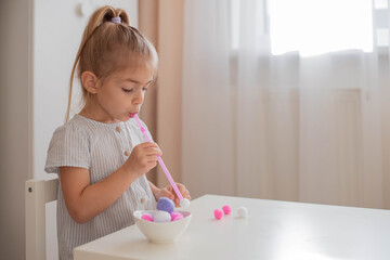 Straw and pom poms counting game for preschool.Child is trying to move pom poms with straw....