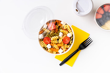 Pasta, coffee and fruits in taking away boxes on white table