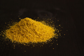 A slide of yellow turmeric or curry spice powder on a black wooden surface. Copy space