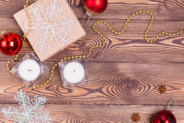 Christmas and New Year holiday background. Decor with gifts wrapped in kraft paper, candles, Christmas decorations, beads, snowflakes, on a wooden table. Flat lay, empty space