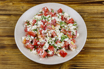 Tasty salad of tomato, cottage cheese, dill and olive oil on wooden table