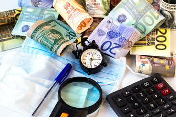 Clipped Euro,Usa and Turkish Banknotes on white with alarm clock,calculator,pen,magnifying glass and medical masks.Conceptual image is on the effects of the epidemic for country economies