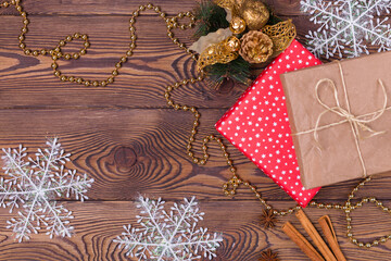 Christmas and New Year holiday background. Decor with gifts, fir branches, cones, Christmas decorations, beads, snowflakes, cinnamon sticks on a wooden table. Flat lay, empty space