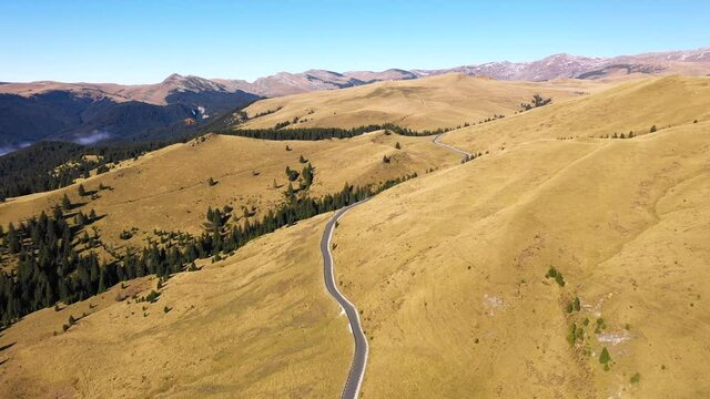 Aerial view of a country road through rural rolling hills and mountain. High altitude road. Highway on the mountain. Mountain forest with fog and countryside asphalt road. Travel by car. Road trip.