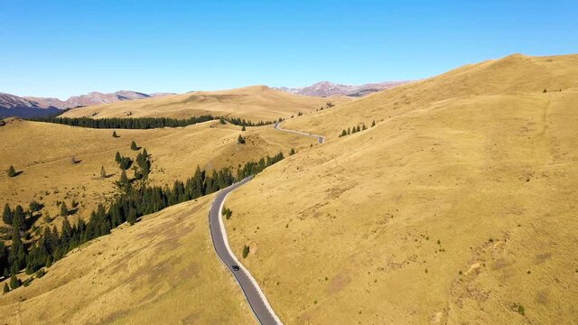 Aerial view of car driving down country road through rural rolling hills and mountain. High altitude road. Highway on the mountain. Mountain forest with fog and countryside asphalt road. Travel by car