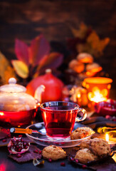 Glass cup of hot red tea and fresh homemade delicious apple cookies on rustic autumn background