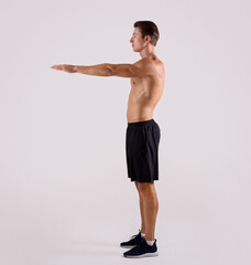 Side view of young strong guy with naked torso and prominent muscles doing aerobic warm up on light...